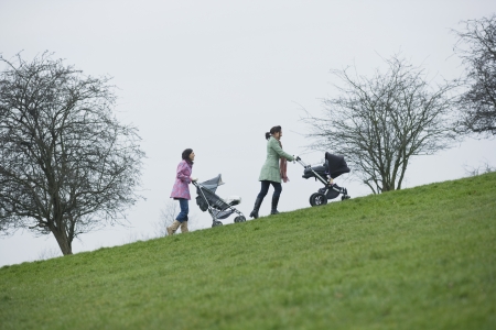 Two mothers pushing stroller uphillの写真素材