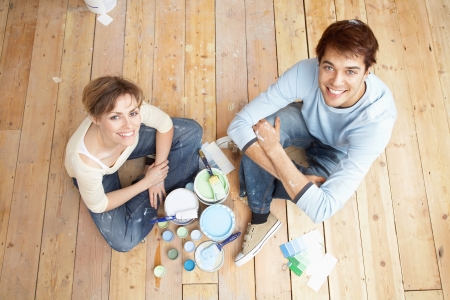 Couple sitting on floorboards amongst paint pots view from aboveの写真素材