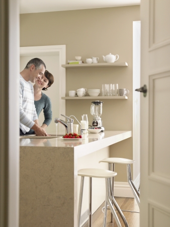Smiling couple in kitchen seen through open doorの写真素材