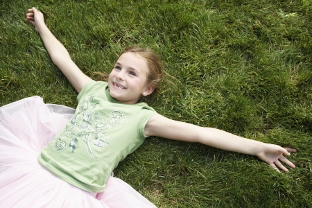 Girl wearing tutu lying on grass view from aboveの写真素材
