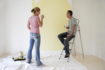 Couple drinking coffee and admiring freshly painted wallの写真素材
