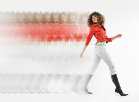 Woman with curly hair walking  in studio multiple exposure