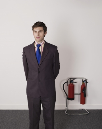 Businessman Standing Near Office Fire Extinguisherの写真素材