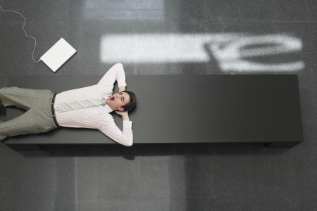 Tired Businessman Lying Down on Deskの写真素材