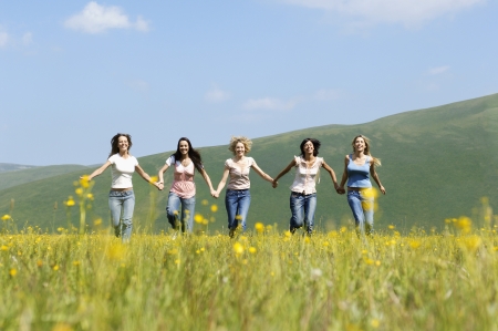 Group of friends running through mountain field, front viewの写真素材