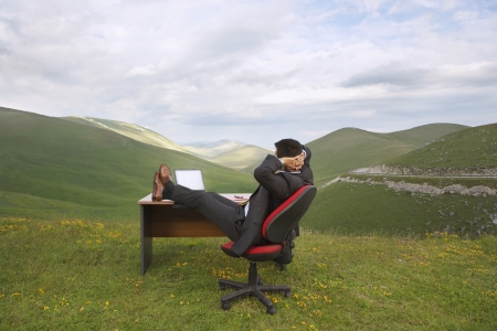 Businessman Sitting at a Desk in a Fieldの写真素材
