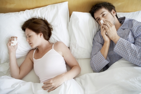 Couple with Colds Lying in Bed high angle viewの写真素材