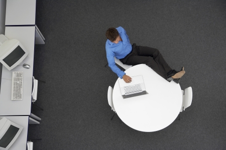 Man Using Laptop in computer room overhead viewの写真素材