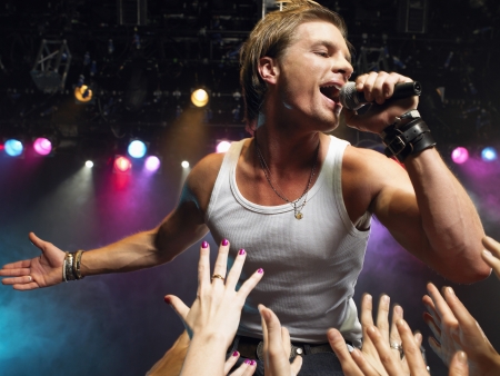 Young Man Singing on stage in concert close to adoring fans low angle viewの写真素材