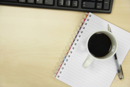 Coffee mug and pen on desk by computer overhead view close upの写真素材