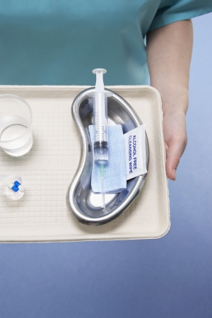 Medical surgeon holding tray with syringe and medicationの写真素材
