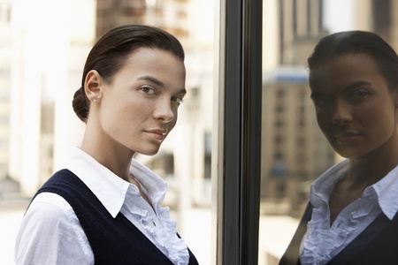 Woman standing outdoors reflected in window head and shoulders
