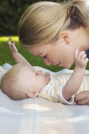 Mother and baby on rug in gardenの写真素材