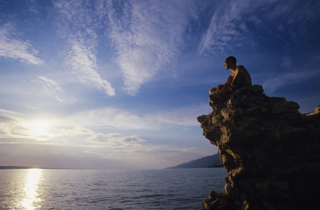 Man sitting on rock overlooking oceanの写真素材