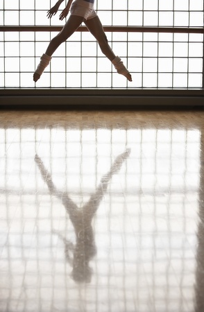 Ballerina in mid-air window and reflectionの写真素材