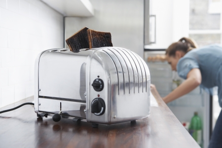 Burned toast in toaster woman in backgroundの写真素材