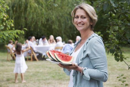 Woman Serving Watermelon at Garden Partyの写真素材
