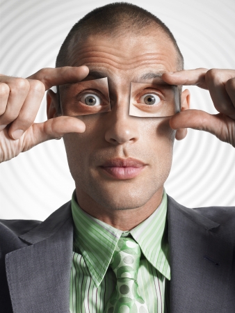 Businessman holding photos of eyes in front of his own eyesの写真素材