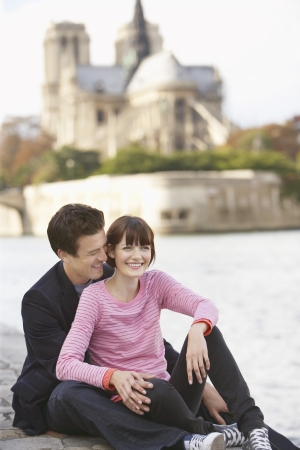 Paris France Couple sitting on river bank in front of Notre Dame Cathedralの写真素材