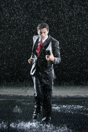 Businessman holding binder running in Rainの写真素材