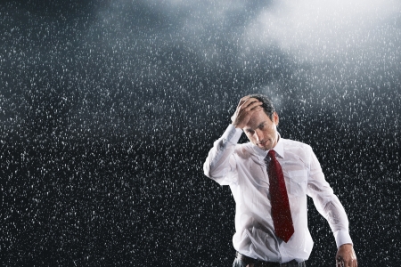 Businessman running hands through wet hair standing in the Rainの写真素材
