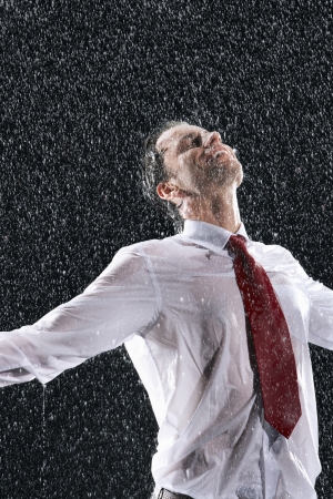 Businessman standing arms spread facing incoming rainの写真素材
