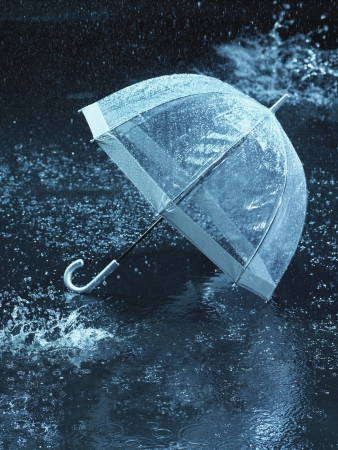 Unused umbrella lying on ground being rained uponの写真素材