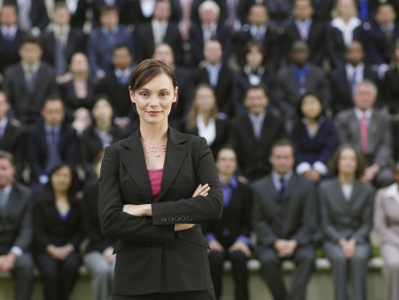 Business woman standing in front of business people sitting in bleachers, portraitの写真素材