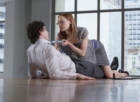 Woman seducing man on office floorの写真素材