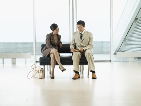 Businesspeople Sitting on Bench in airport looking over documentsの写真素材