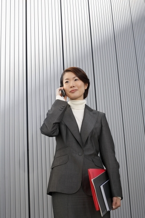 Businesswoman holding paperwork using Cell Phoneの写真素材