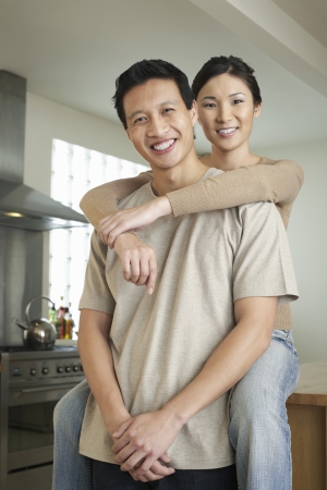 Wife sitting on countertop arms around standing husbandの写真素材