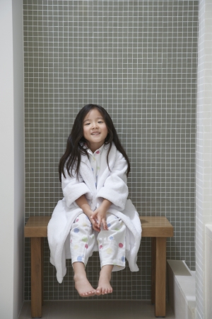 Young Girl wearing bathrobe Sitting on Bench by Bathtubの写真素材