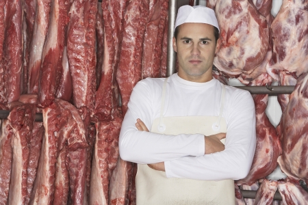 Butcher Standing arms crossed in front of raw meat  in Meat Lockerの写真素材