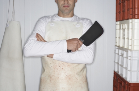 Butcher standing arms crossed  Holding Cleaver next to stack of crates mid sectionの写真素材