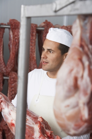 Butcher holding slab of meat Working in Meat Lockerの写真素材