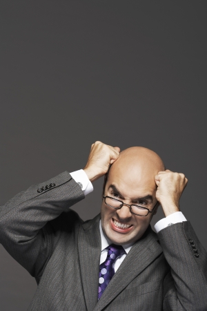Bald businessman fists on head pounding head making a faceの写真素材