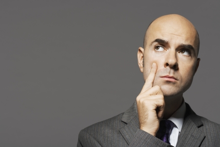 Bald businessman with hand on chin thinkingの写真素材