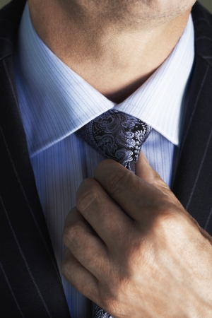 Middle-aged businessman in full suit adjusting tie  mid sectionの写真素材