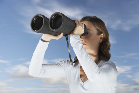 Mid-adult woman standing outside looking through large pair of binocularsの写真素材