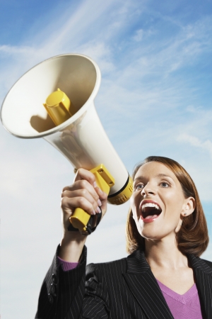 Smiling Mid-adult woman shouting through megaphone outsideの写真素材