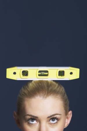 Woman balancing spirit level on her head against dark background high sectionの写真素材