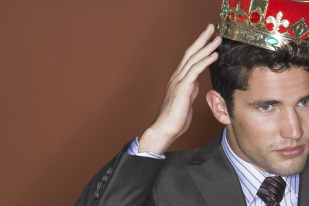 Man putting on crown against brown background close-upの写真素材