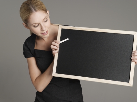 Portrait of young female teacher holding blackboardの写真素材