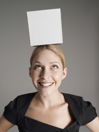 Young woman in black dress with white box on her headの写真素材