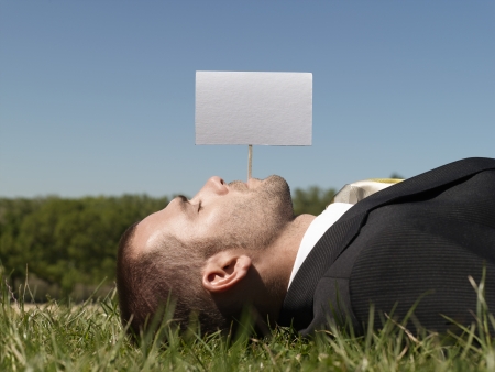 Young man lying on grass by blank signの写真素材