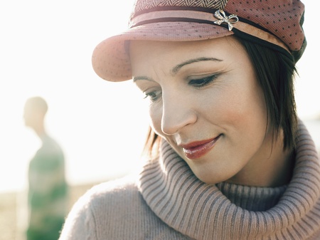 Woman standing on beach with man in background portrait close up