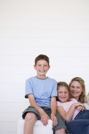 Portrait of mother and children sitting on couch in weather boarded roomの写真素材