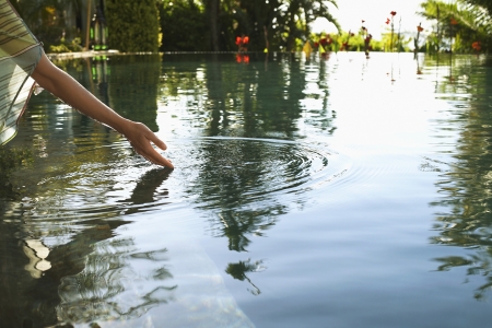 Young woman reaching out to touch lake croppedの写真素材