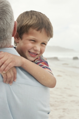 Father carrying son (5-6) on beach, close-upの写真素材